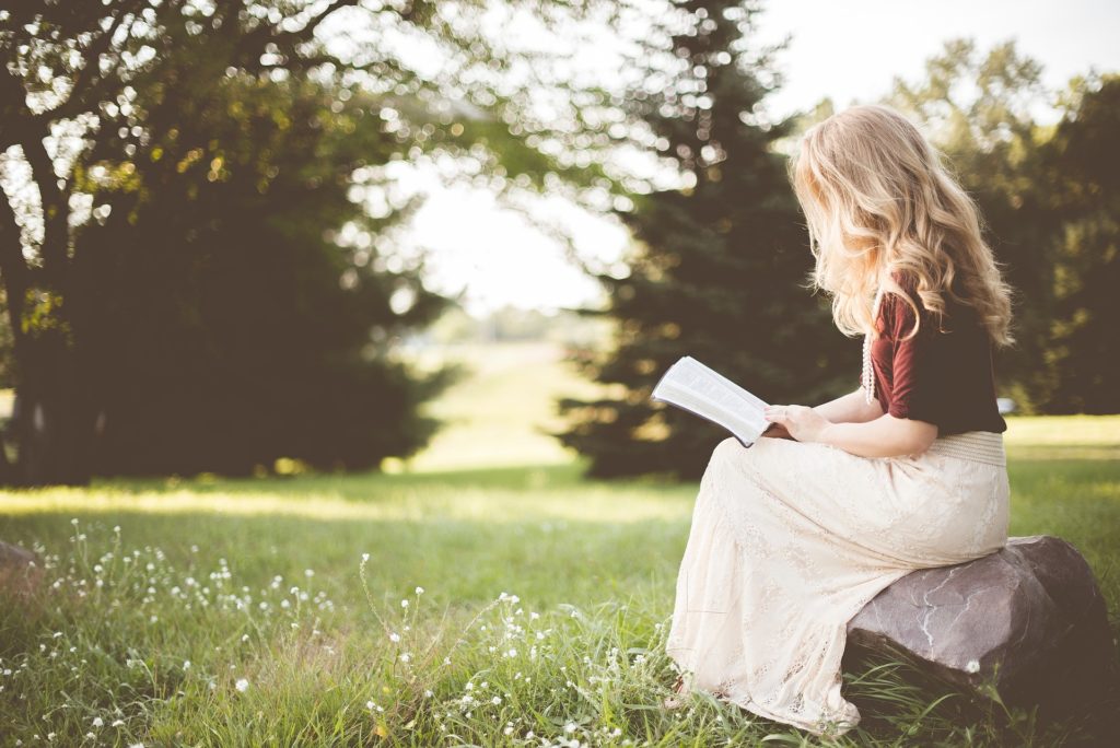 Cette image issue de Pixabay, stocksnap-girl-2604837_1920 montre une femme blonde en train de lire, assise sur un rocher au bord d'un champs. Le but est d'illustrer les bienfaits de la lecture profonde. 
